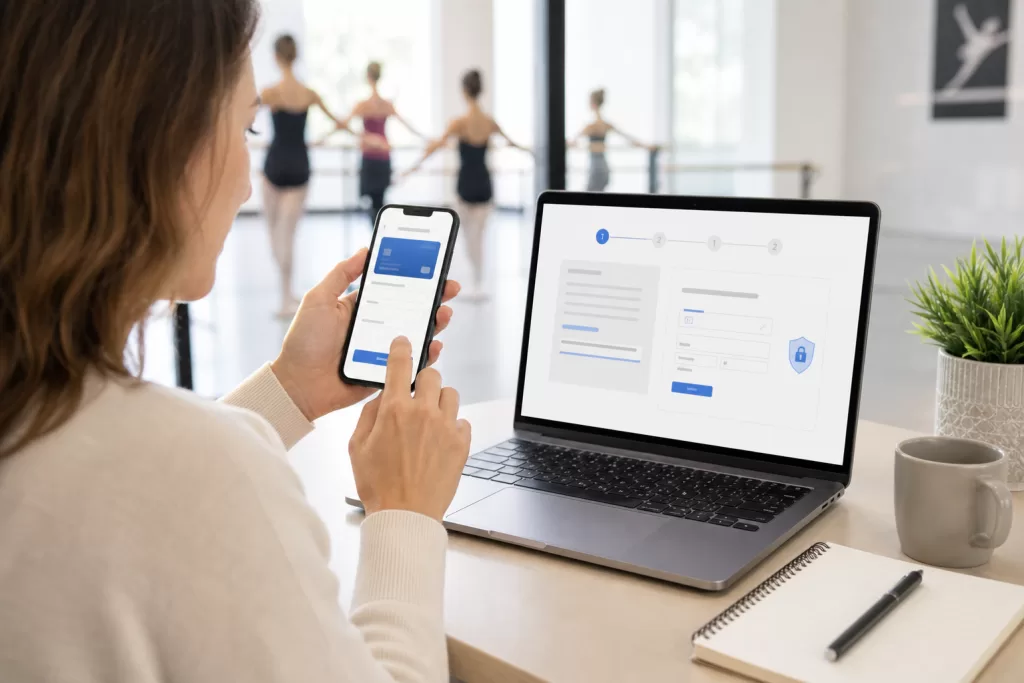 Parent reviewing a dance studio payment on a phone with a laptop nearby