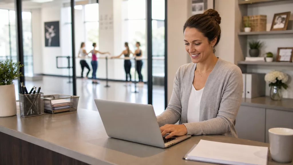 Dance studio manager reviewing payment activity on a laptop at the front desk