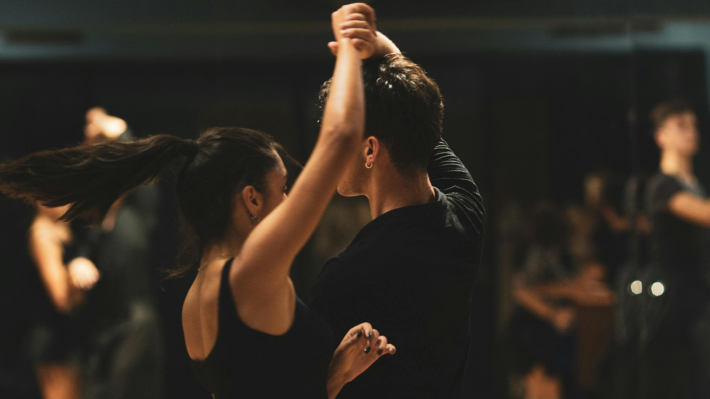 A man and a woman are in the studio, practicing for their ballroom performance.