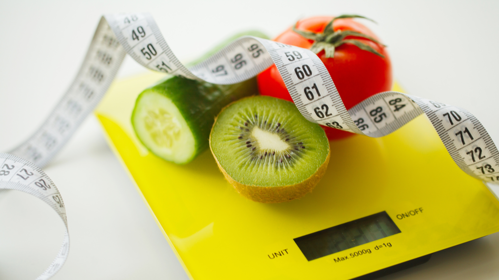 Weighing cucumber, kiwi and apple with the yellow weighing scale.
